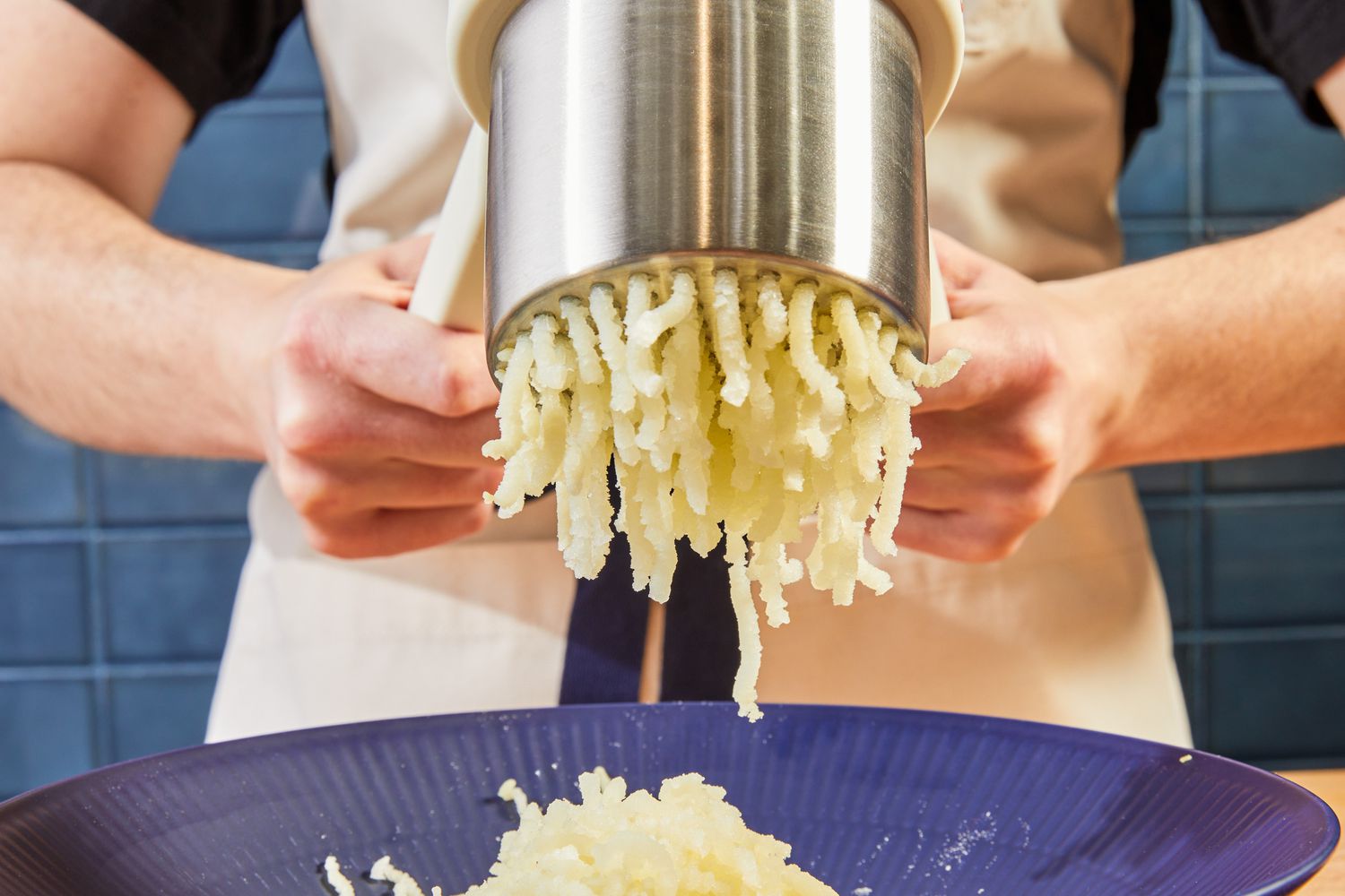A person using the Joseph Joseph potato ricer to rice potatoes. 