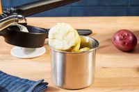 Peeled whole potatoes in the hopper of a potato ricer.