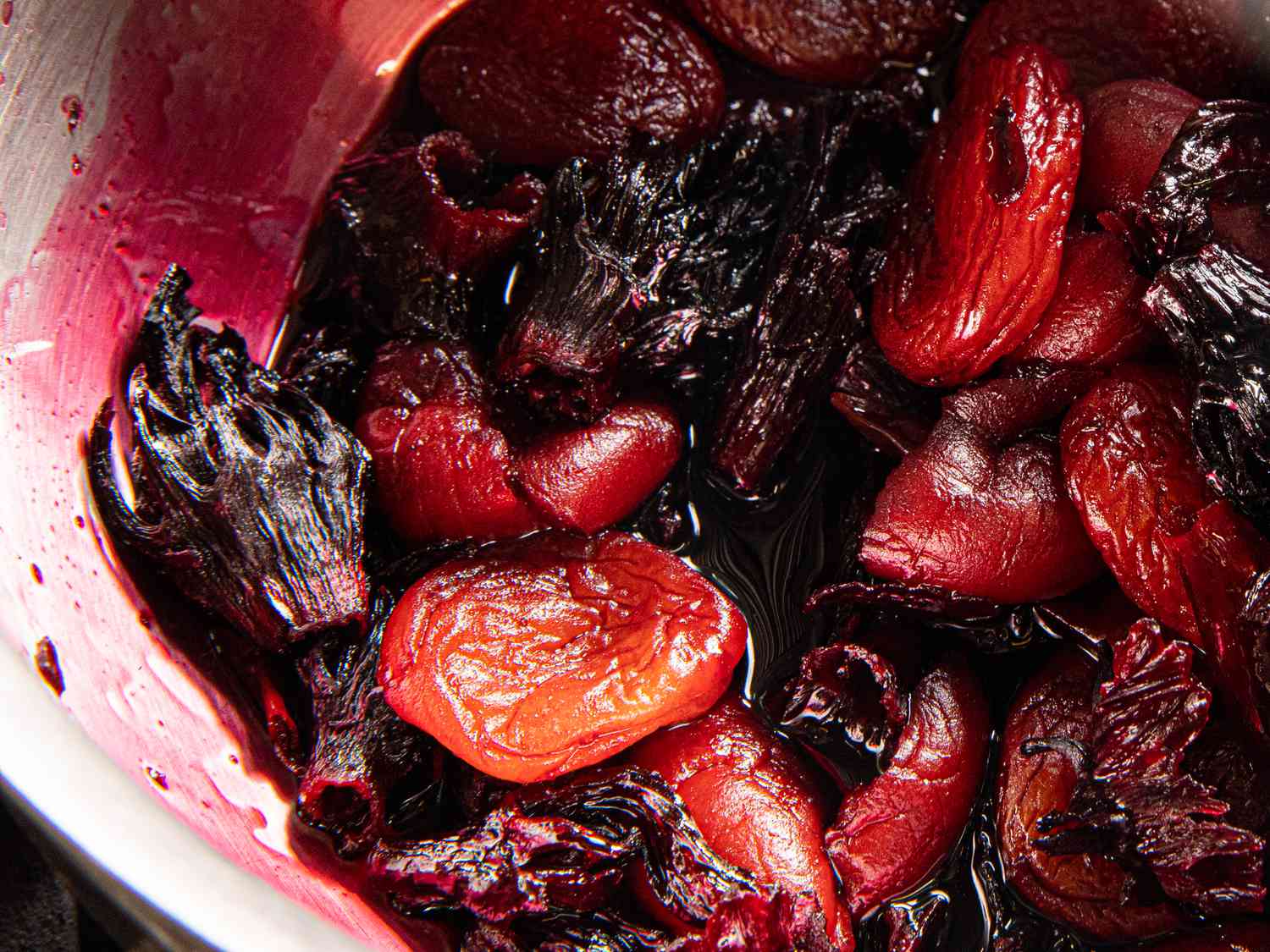 The simmered chamoy ingredients in a saucepan; the hibiscus has dyed everything a deep purple color, and the apricots look plump