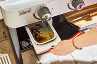 A person pulls the drip tray out of the Weber 36 Inch Gas Griddle