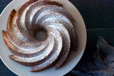 Overhead view of a pudín Mary cake, served on a white plate and dusted with confectioners' sugar.