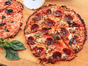 Two Extra-Crispy Bar-Style Tortilla Supreme Pizzas, cut into wedges on a wooden cutting board. 