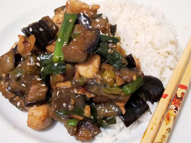 Closeup of sesame chicken and eggplant, served with white rice.