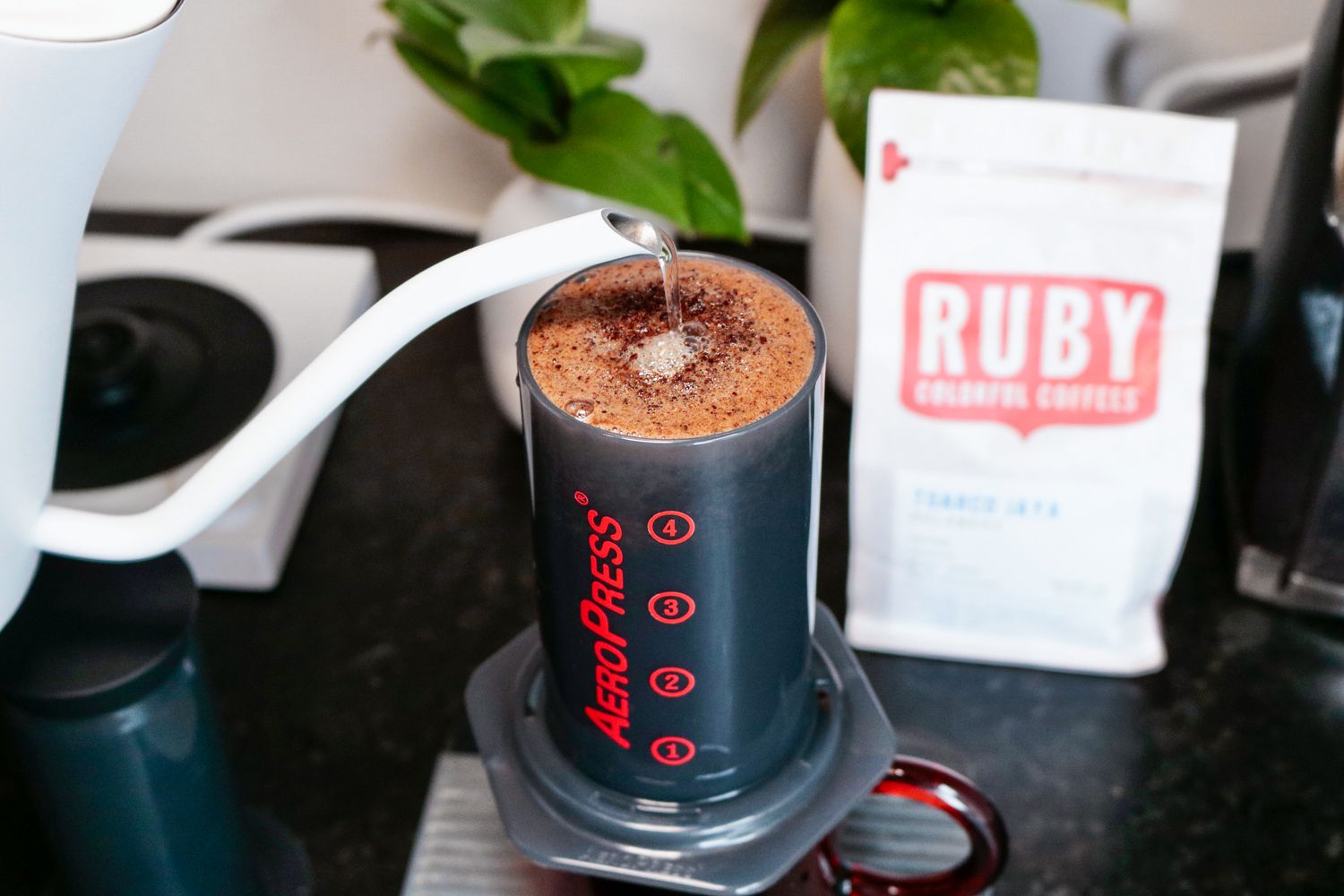 Water being added from a gooseneck kettle into an Aeropress
