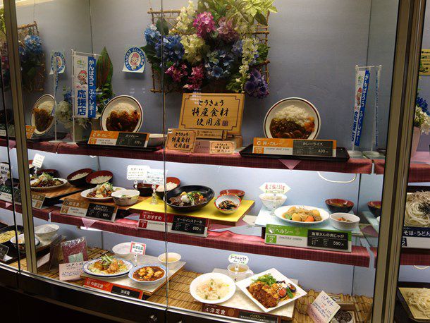 A glass display of plated plastic samples of various Japanese dishes at Tocho