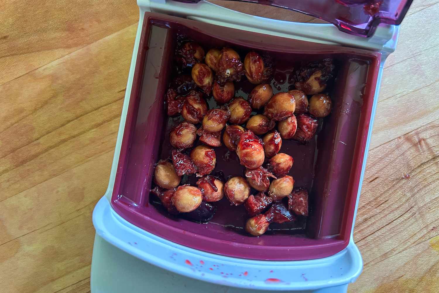 The catch basin of the OXO Multi Cherry Pitter full of cherry pits.