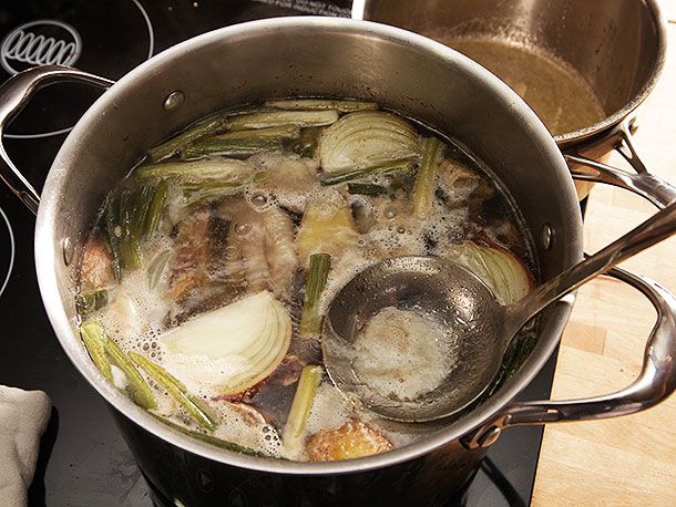 Skimming scum off surface of stockpot.