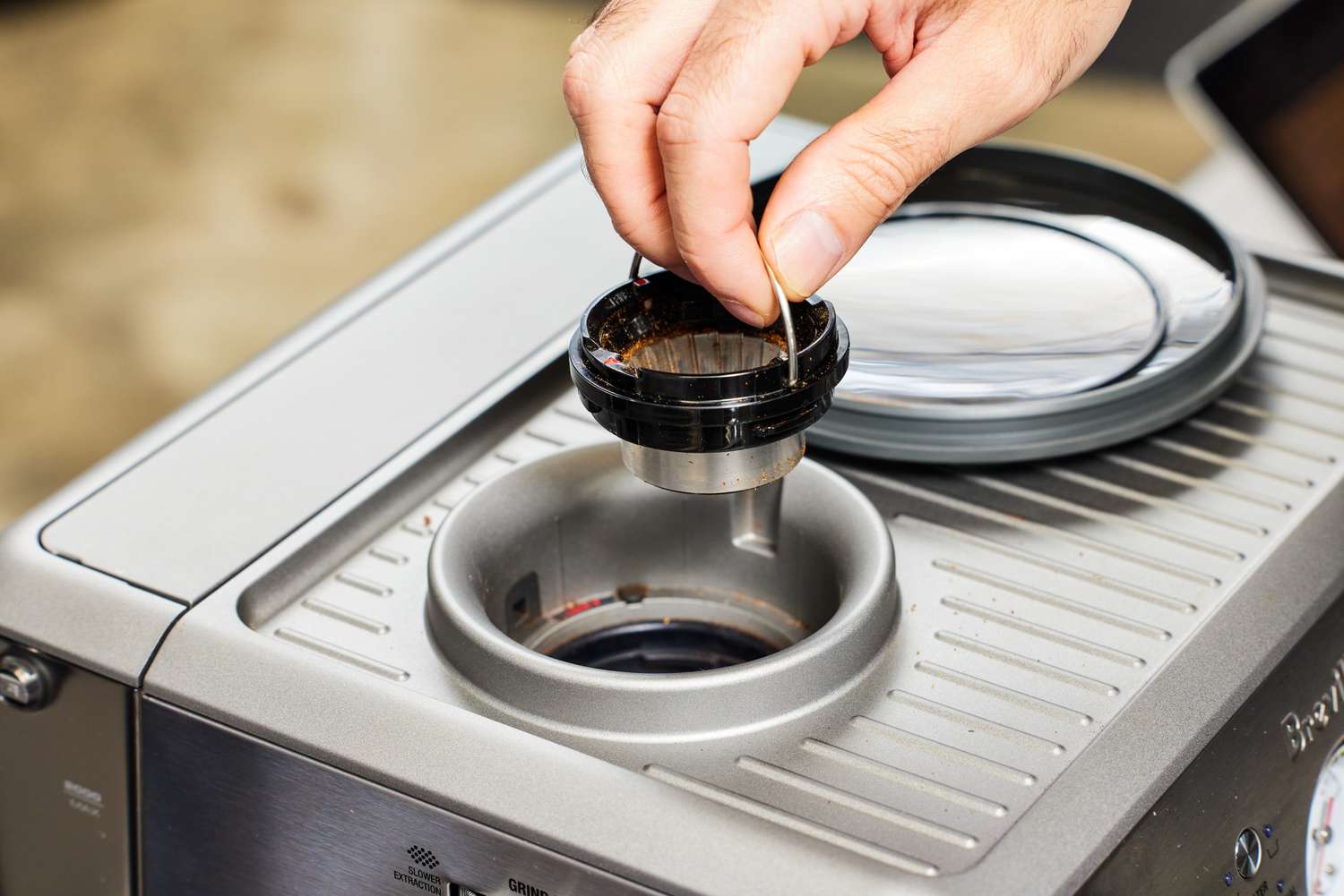 Closeup of a person lifting up one section of the Breville Barista Express Impress