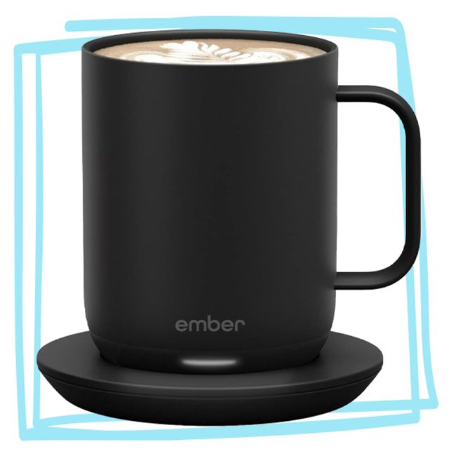 A black mug branded Ember with a latte inside placed on a charging coaster