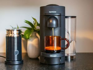 A wide-angle shot of a Nespresso machine brewing into a mug with a milk frother beside it