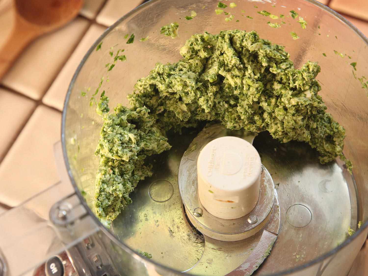 A food processor holding a fully processed blend of herbs and butter.
