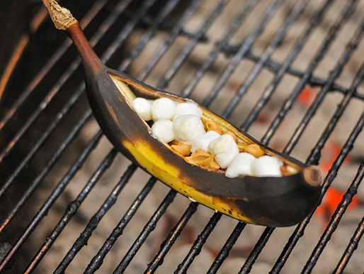 Closeup of a grilled banana boat on the grate above glowing coals.