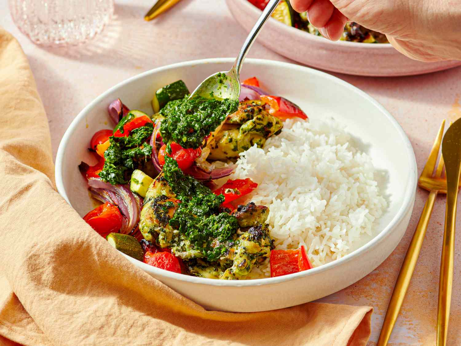 A plate of chimichurri chicken thighs with rice and grilled vegetables