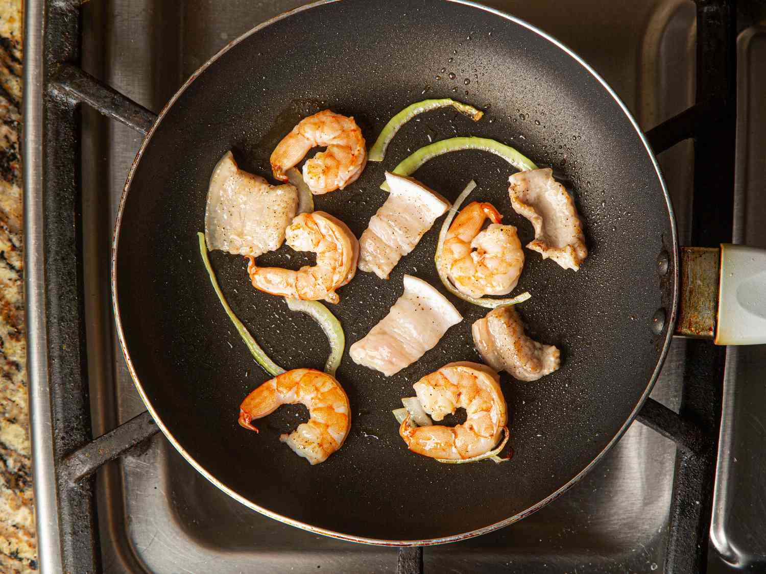 Overhead view of shrimp and pork in skillet