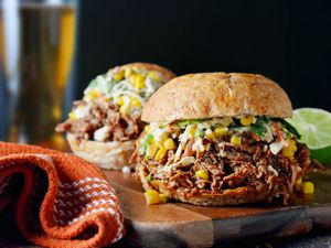 Profile view of a chorizo-spiced pulled pork sandwich with Mexican street corn slaw.
