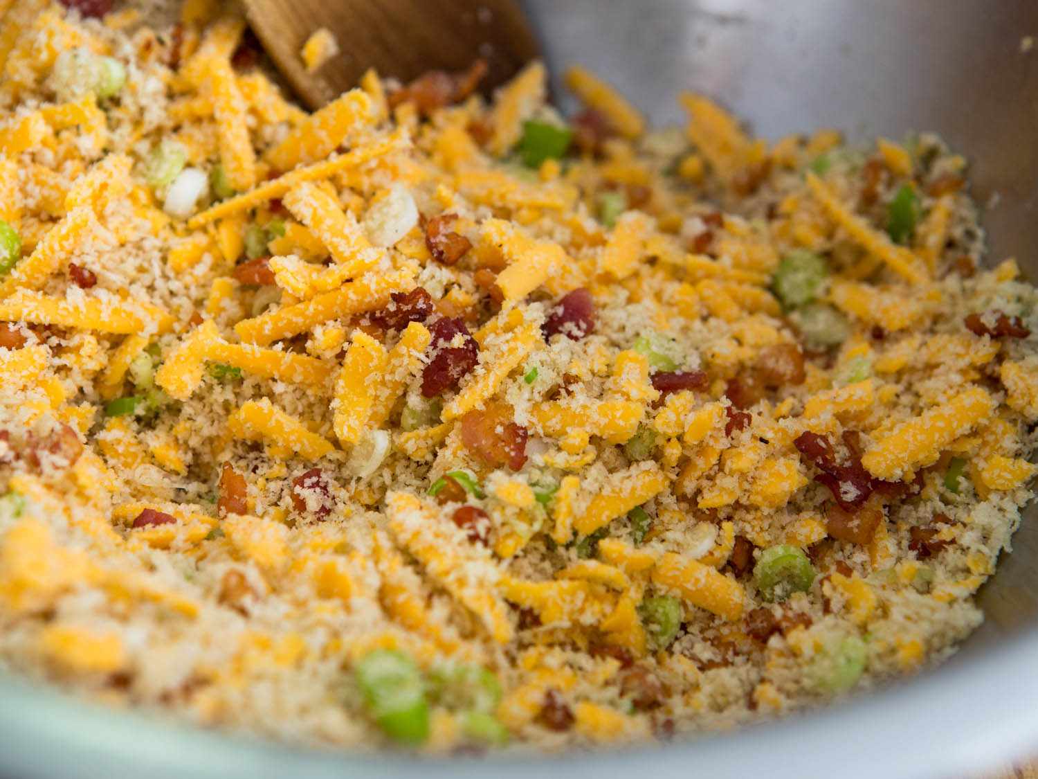 Mixture of bread crumbs, scallions, bacon, and shredded cheddar in bowl.