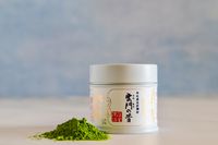 A container of Ippodo Tea Ummon Matcha next to a pile of the powder