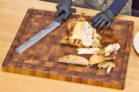 Person carving a roasted chicken on a Yes4All Teak Cutting Board