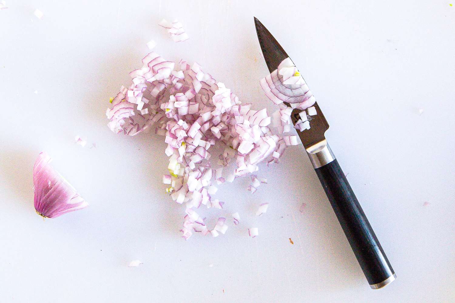 Finely diced onion next to a Shun knife on a cutting board
