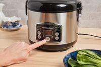 a person pressing a setting on a rice cooker