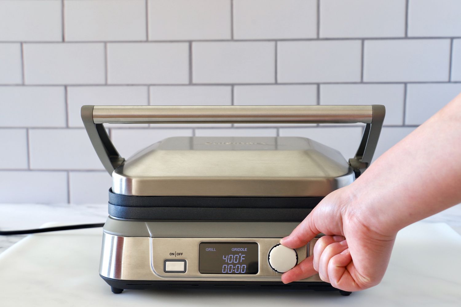 A person adjusting the temperature controls of the Cuisinart griddler.