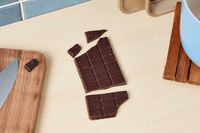 An unwrapped dark chocolate bar on a kitchen countertop.