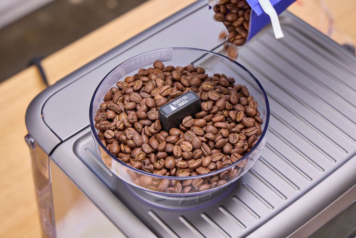 Espresso beans are poured into the Breville The Barista Pro Espresso Machine coffee grinder