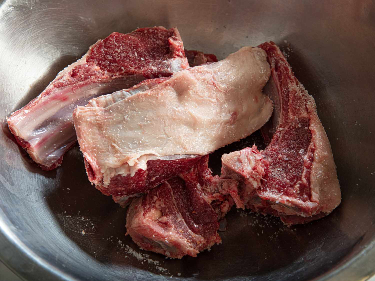 Raw meat pieces in a steel bowl prepared for cooking process