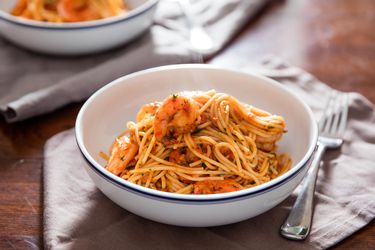 Two white bowls of shrimp fra diavolo with spaghetti on a dining table. 