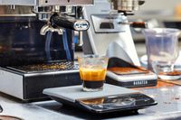 An espresso in a glass cup next to the Gaggia Classic Pro Espresso Machine