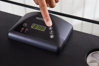 Hand pressing a button on the Masterbuilt MB20072918 40-Inch Digital Electric Smoker