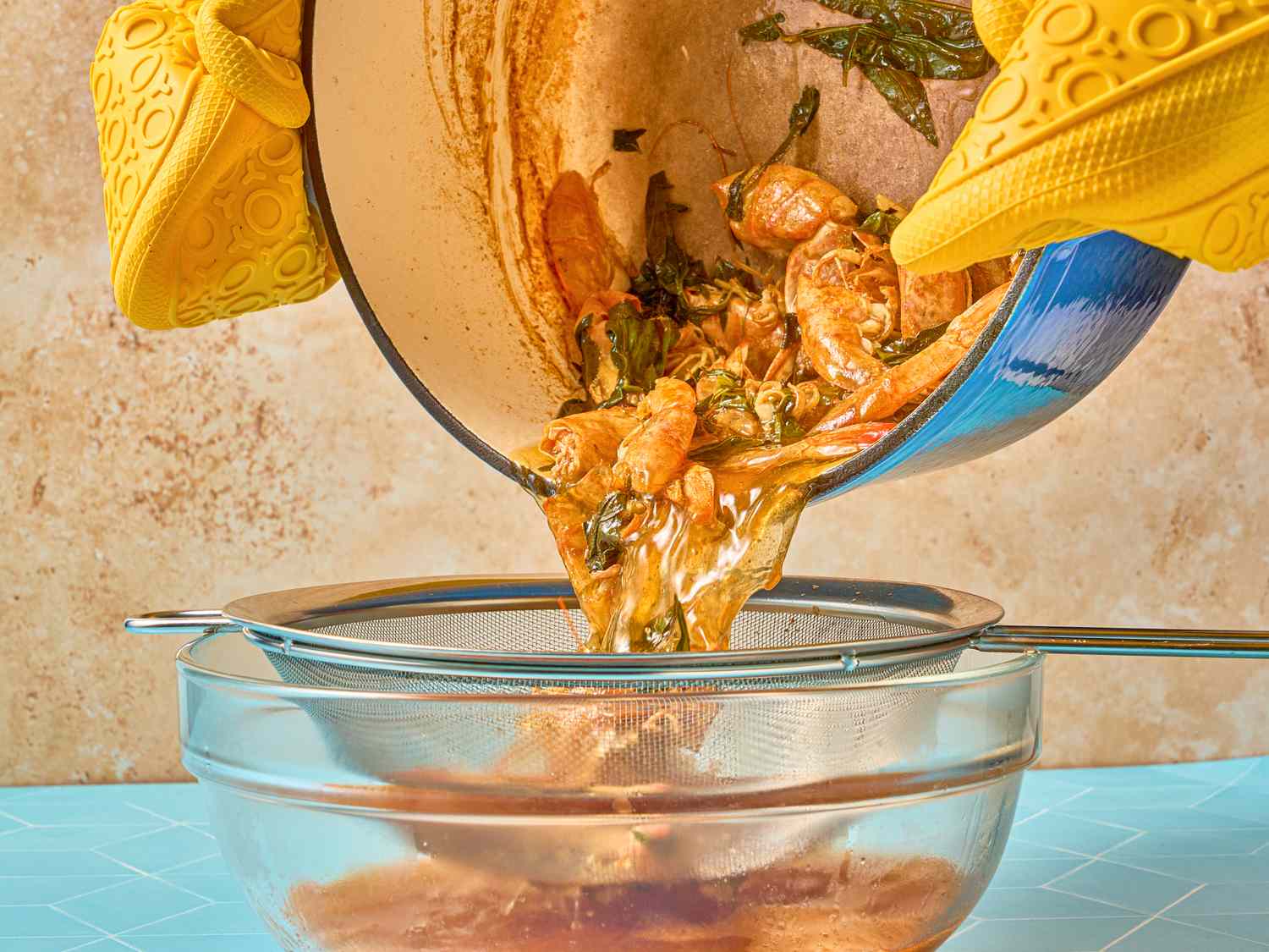 Straining curry laksa ingredients into a glass bowl using a sieve