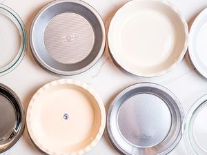 An overhead view of pie pans on a white surface