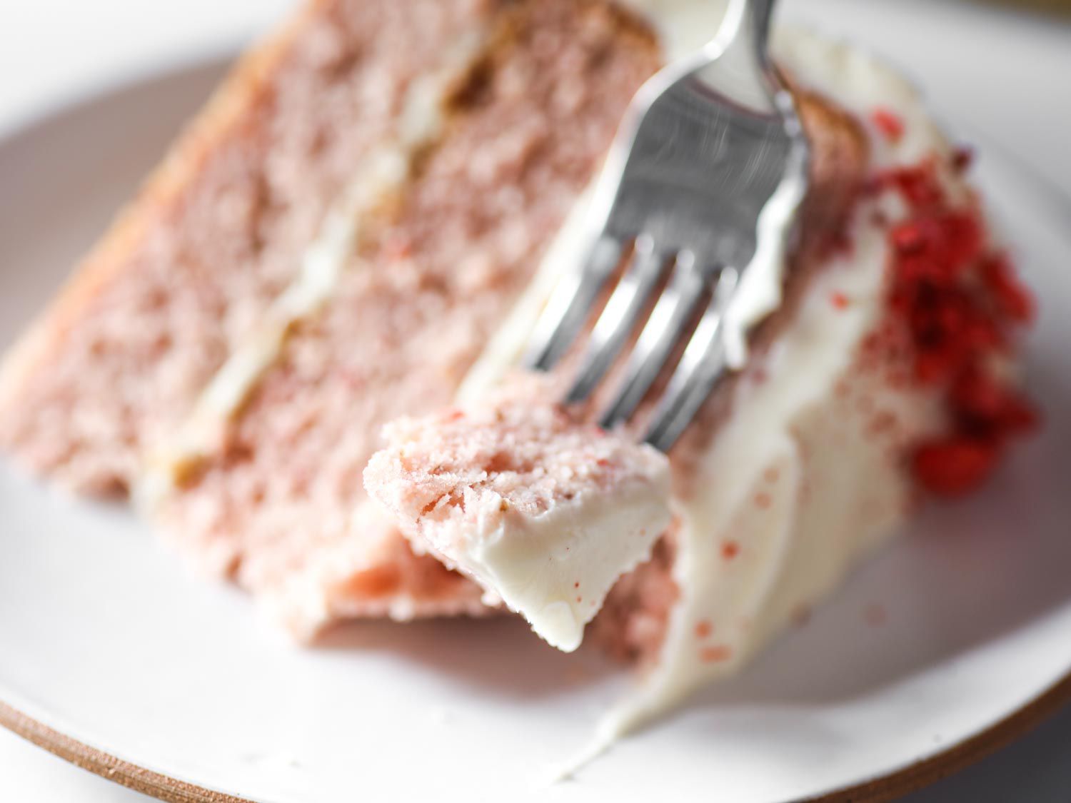 Close-up of a fork spearing a bite of strawberry cake.