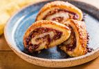 Three almond-raspberry rugelach on a ceramic plate. 