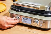 Person turning knob on Breville The Smart Waffle Pro 4-Slice Waffle Maker