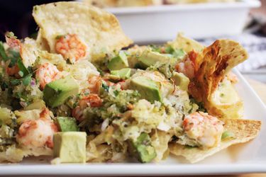Profile closeup of Shrimp Nachos With Tomatillo Salsa, served on a square white plate.
