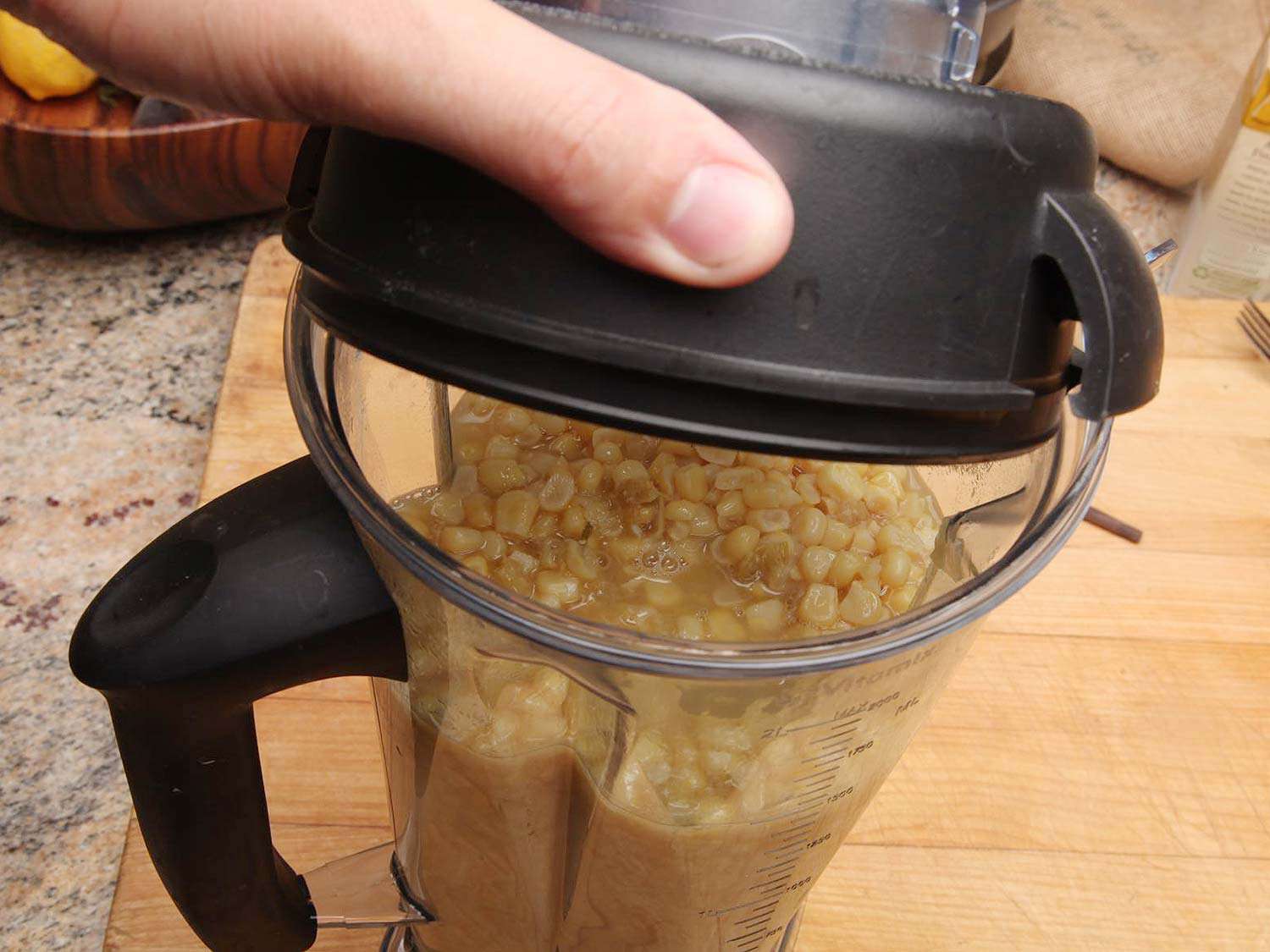Putting a lid onto a blender pitcher full of corn soup about to be blended.