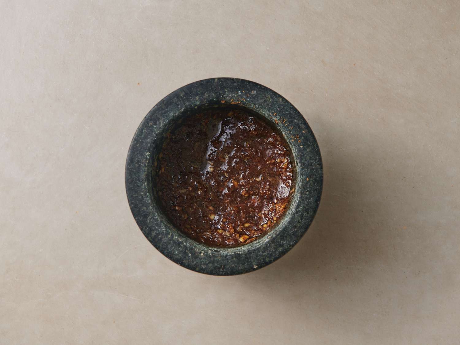 White peppercorns, salt, lemongrass, shallot, garlic, and palm sugar crushed into a rough paste inside mortar