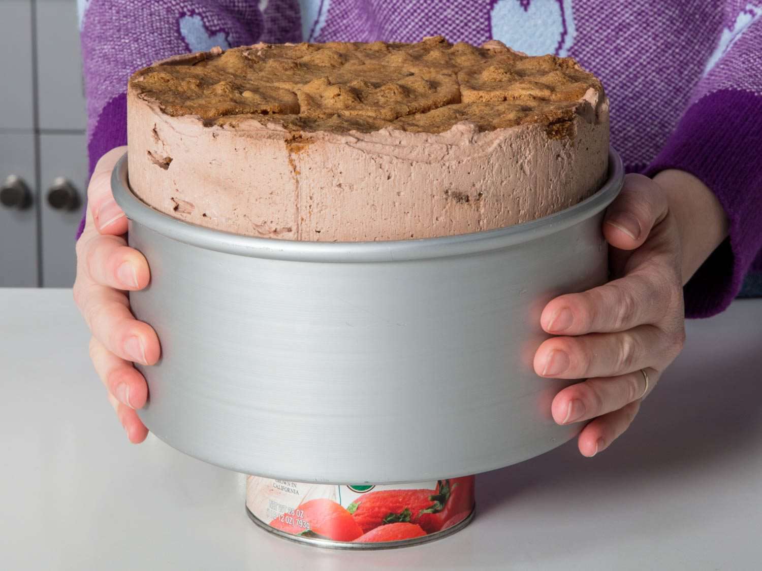 Unmolding the icebox cake over a can of tomatoes to remove the sides.