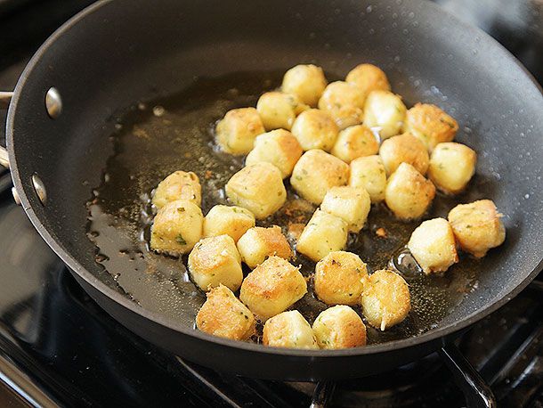Closeup of Parisian gnocchi being sautéed in a nonstick skillet.