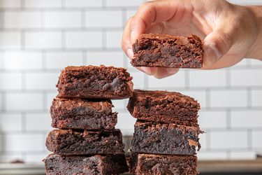 A stack of brownies with one being held above the stack