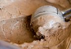 Closeup of mocha cashew ice creambeing scooped from a storage container.