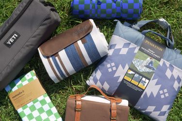 six picnic blankets folded up on grass