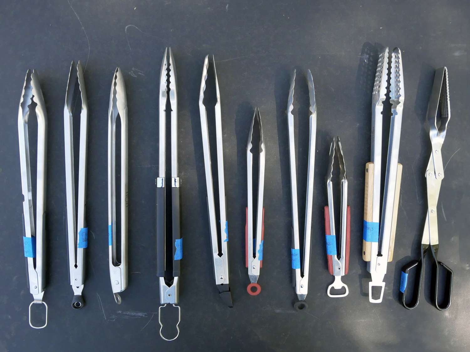 lineup of tongs on a black surface