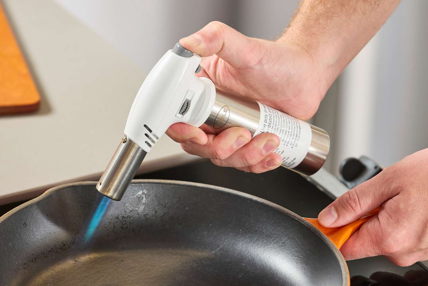 someone using a kitchen torch to heat a skillet