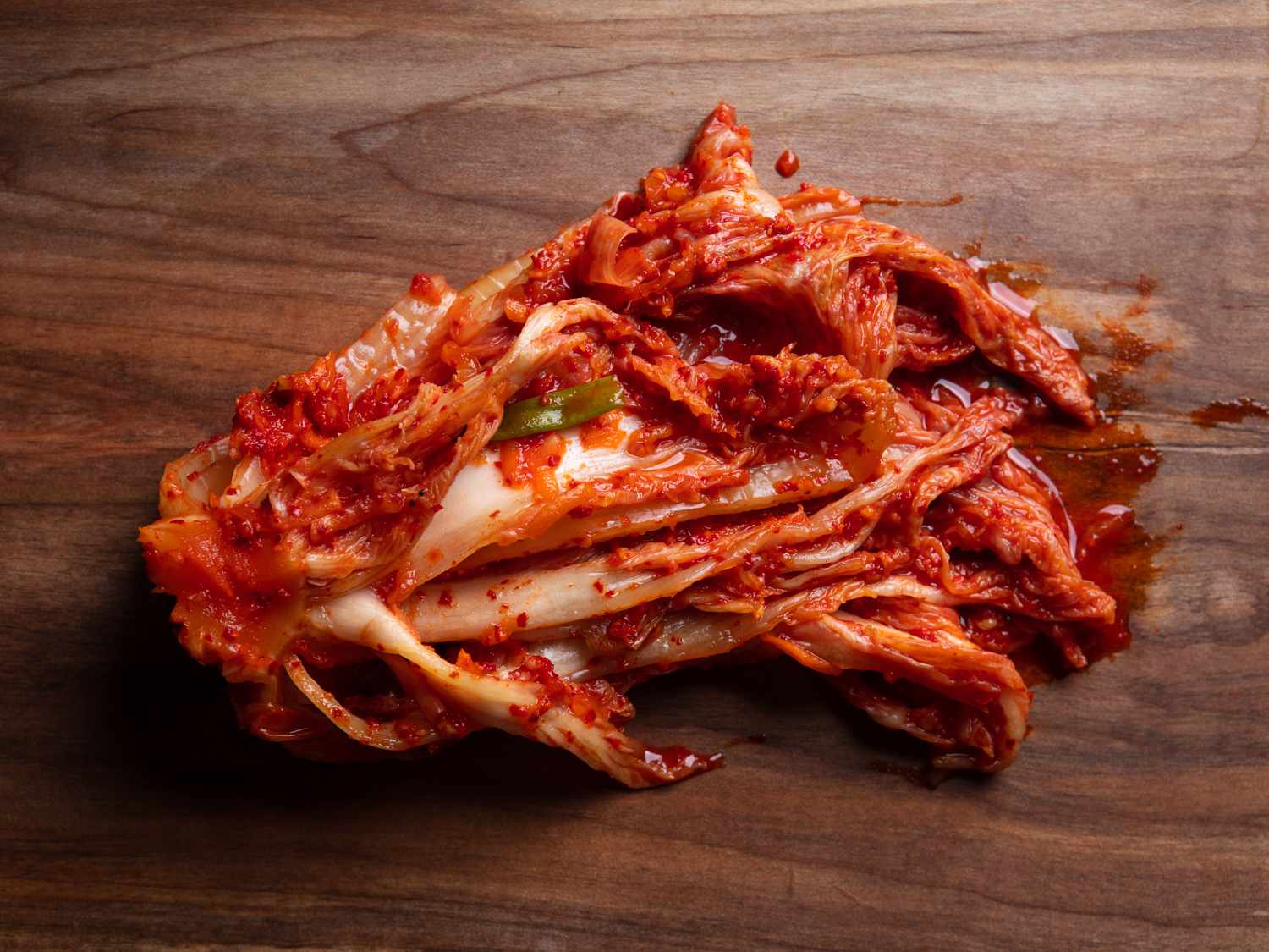 a packet of baechu kimchi removed from the fermentation vessel and unrolled on a wooden cutting board