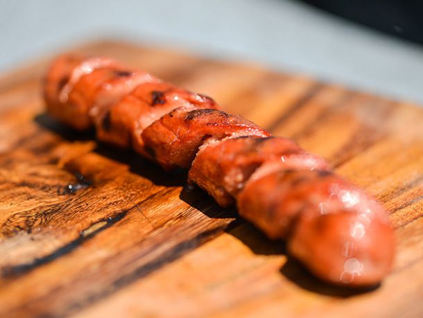 A spiral-cut skinless hot dog, grilled and sitting on a cutting board.