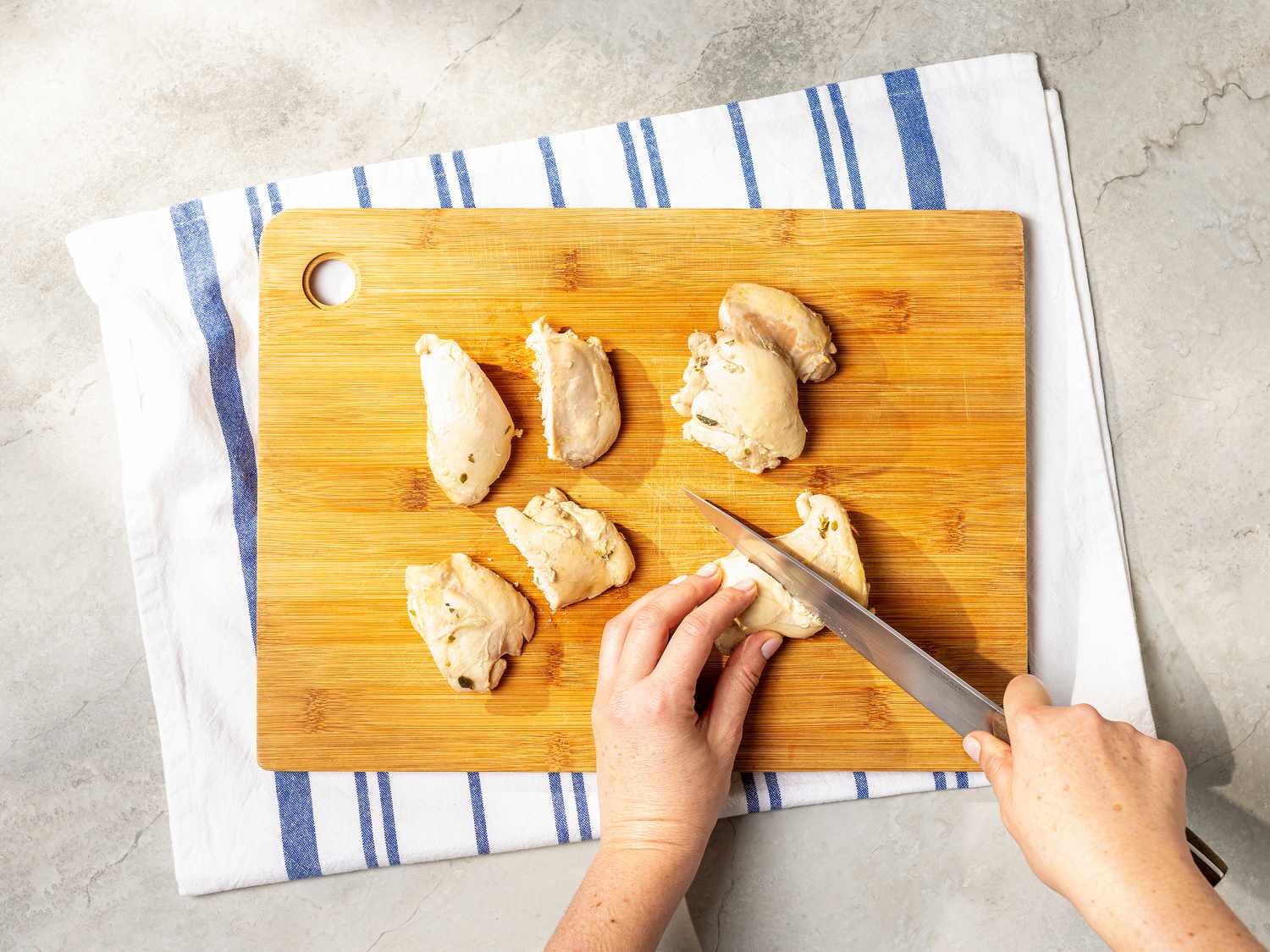 Cutting cooled poached chicken into 8 pieces 