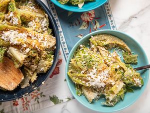 Two servings of a salad featuring greens grated cheese and a wooden spoon
